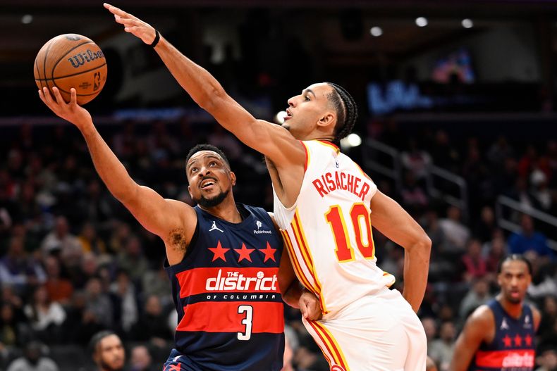 CJ McCollum, base de los Wizards de Washington, dispara frente a Zaccharie Risacher, de los Hawks de Atlanta, en el encuentro del jueves 25 de noviembre de 2025 (AP Foto/John McDonnell)