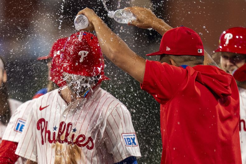 Trea Turner, de los Filis de Filadelfia, es empapado por sus compañeros tras conseguir el hit decisivo en el juego ante los Bravos de Atlanta, el sábado 38 de agosto de 2025 (AP Foto/Chris Szagola)