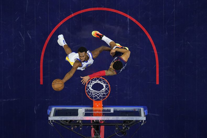 Andrew Wiggins, izquierda, de los Warriors de GOlden State, se alza para disparar a la canasta, mientras KJ Martin, de los 76ers de Filadelfia, defiende durante la primera mitad del juego de baloncesto de la NBA, el miércoles 7 de febrero de 2024, en Filadelfia. (AP Foto/Matt Slocum)