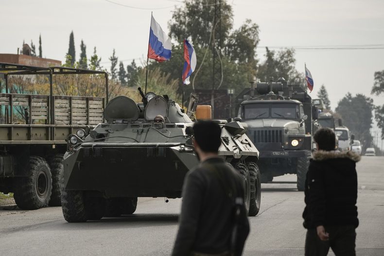 En esta imagen de archivo, combatientes sirios observan vehículos blindados rusos en las inmediaciones de la Base Aérea Hmeimim, que está operada por Rusia, en Hmeimim, en el sureste de la provincia de Latakia, Siria, el 16 de diciembre de 2024.(AP Foto/Leo Correa, archivo)