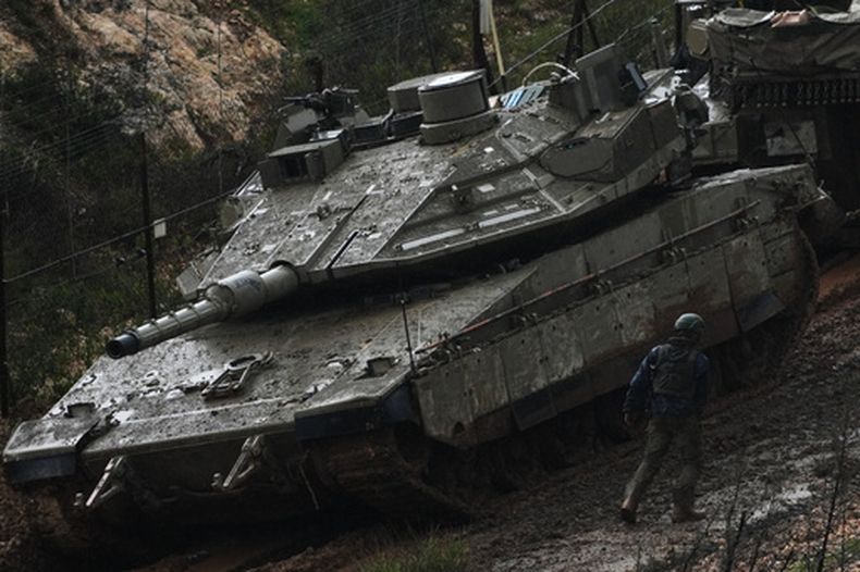 Un soldado israelí camina junto a un tanque en el norte de Israel, cerca de la frontera con Líbano, el sábado 21 de marzo de 2026. (Foto AP/Ariel Schalit)