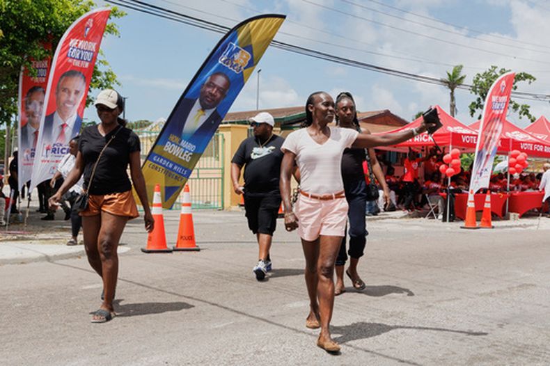 Varios votantes salen de un centro electoral en Garden Hills tras emitir su sufragio en una elección general en Nassau, Bahamas, el martes 12 de mayo de 2026. (AP Foto/Tim Aylen)
