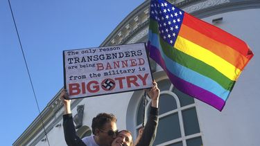 ARCHIVO - Nick Rondoletto, izquierda, y Doug Thorogood, ambos de San Francisco, ondean una bandera multicolor y sostienen un cartel durante una protesta realizada en San Francisco el miércoles 26 de julio de 2017 para oponerse a una propuesta para prohibir que personas transgénero presten servicio en el ejército de EEUU. (AP Foto/Olga R. Rodriguez, Archivo)