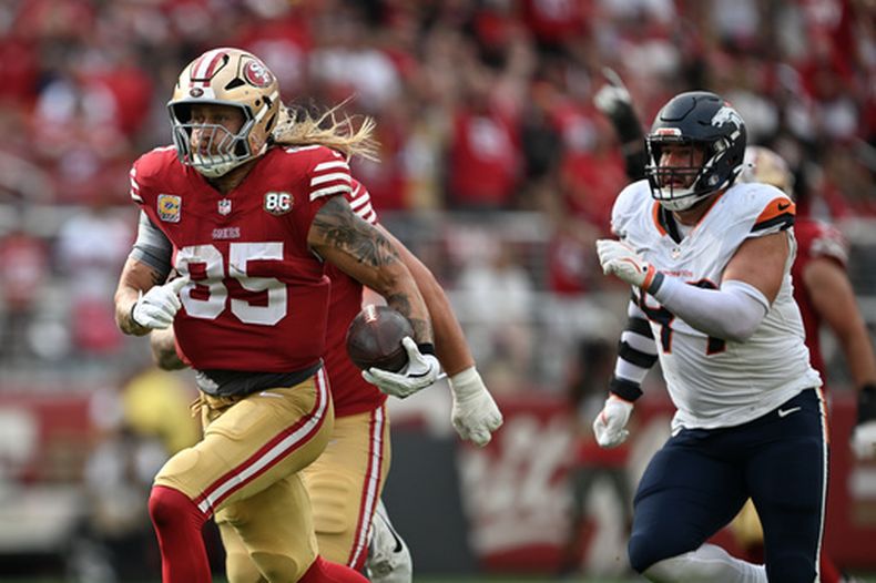 George Kittle (85), ala cerrada de los 49ers de San Francisco, corre por delante de Zach Allen, de los Broncos de Denver, y se escapa para una anotación durante la segunda mitad del partido de la NFL del domingo 4 de octubre de 2026. (AP Foto/Justine Willard)