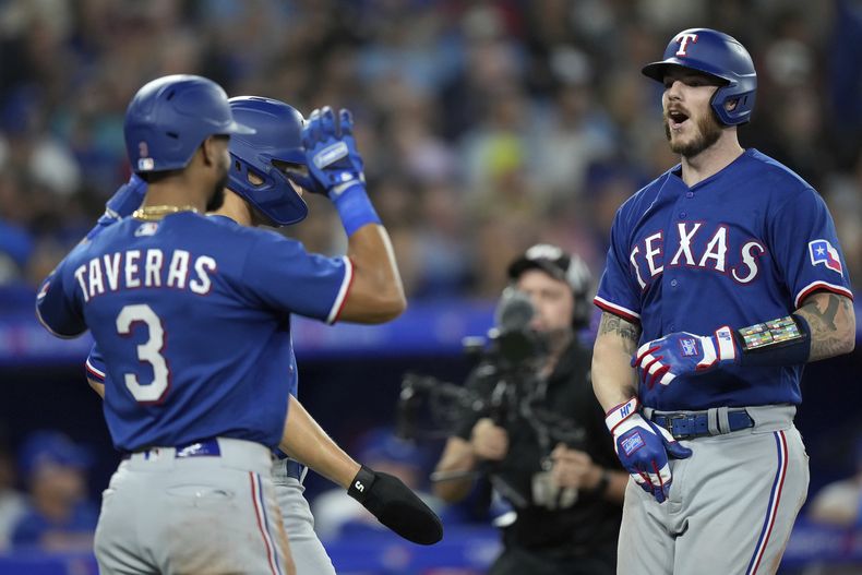 Jonah Heim (derecha) de los Rangers de Texas celebra con su compañero Leody Taveras (3) en el juego ante los Azulejos de Toronto, el lunes 11 de septiembre de 2023, en Toronto. (Nathan Denette/The Canadian Press vía AP)