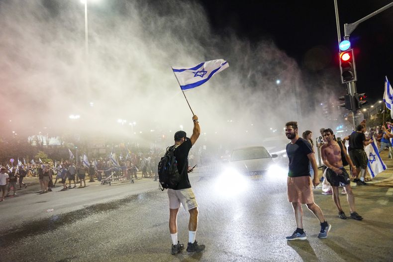 La policía israelí emplea un cañón de agua para dispersar a manifestantes que bloquean una calle en una protesta contra los planes del gobierno del primer ministro, Benjamin Netanyahu, de reformar el sistema judicial, en Jerusalén, el domingo 23 de julio de 2023. (AP Foto/Ohad Zwigenberg)