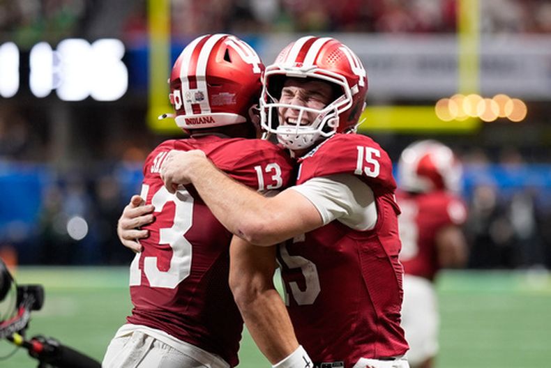 El wide receiver Elijah Sarratt (13), de los Hoosiers de Indiana, celebra su recepción de touchdown con el quarterback Fernando Mendoza (15) durante la segunda mitad del Peach Bowl, la semifinal del fútbol americano universitario de la NCAA, frente a los Ducks de Oregon, el viernes 9 de enero de 2026, en Atlanta. (AP Foto/Mike Stewart)