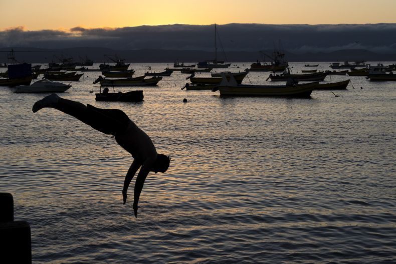 Un hombre se lanza desde un muelle al atardecer en Tongoy, Chile, el martes 21 de enero de 2025. (Foto AP/Matías Basualdo)
