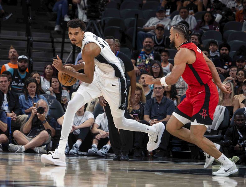 El alero de los Spurs de San Antonio Victor Wembanyama avanza con el balón frente al base de los Rockets de Houston Dillon Brooks en el encuentro del sábado 26 de octubre del 2024. (AP Foto/Michael Thomas)