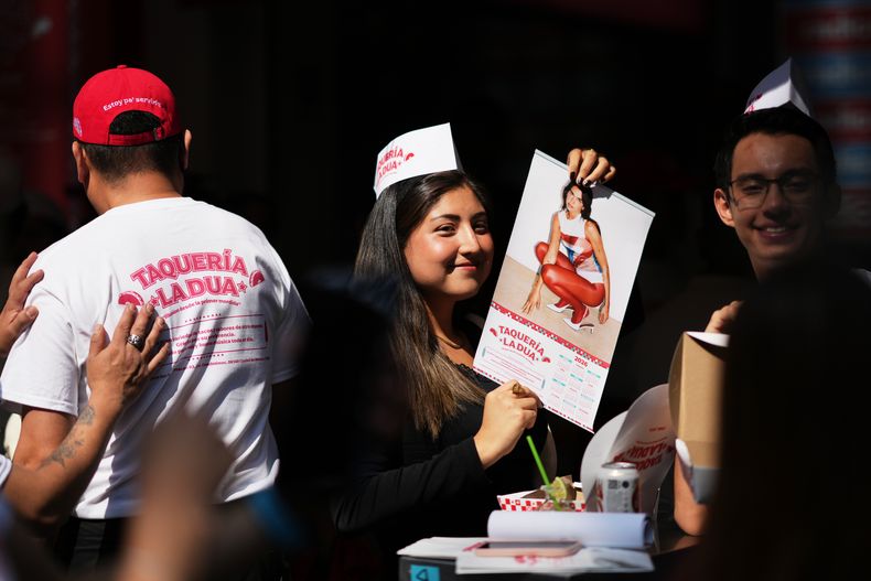 Una clienta sostiene un calendario de Dua Lipa durante la apertura la taquería La Dua de la estrella de la música, un restaurante emergente para sus fans en la Ciudad de México, el lunes 1 de diciembre de 2025. (Foto AP/Eduardo Verdugo)