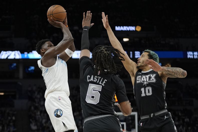 Anthony Edwards, izquierda, de los Timberwolves de Minnesota, tira con una doble marca defensiva de Stephon Castle (5) y Jeremy Sochan (10), de los Spurs de San Antonio, durante la primera mitad del juego de baloncesto de la NBA, el domingo 9 de marzo de 2025, en Minneapolis. (AP Foto/Abbie Parr)