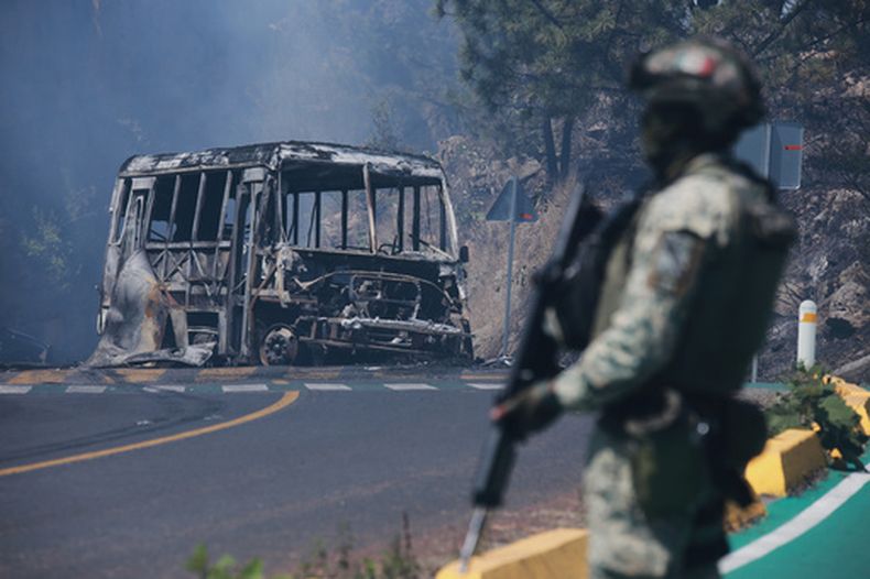 ARCHIVO - Un soldado monta guardia junto a un vehículo calcinado tras ser incendiado en Cointzio, estado de Michoacán, México, el 22 de febrero de 2026, luego de la muerte del líder del Cártel Jalisco Nueva Generación, Nemesio Oseguera, también conocido como El Mencho. (Foto AP/Armando Solís, Archivo)
