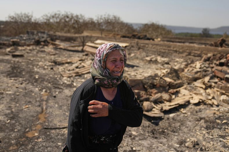 La agricultora Turkan Ozkan llora junto a su casa destruida después de un incendio en Guzelyeli, en las afueras de Canakkale, noroeste de Turquía, el martes 12 de agosto de 2025. (AP Foto/Khalil Hamra)