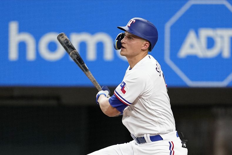 Cory Seager, de los Rangers de Texas, sigue el movimiento después de batear un sencillo productor de una carrera en la segunda entrada del juego de béisbol en contra de los Medias Blancas de Chicago, el miércoles 2 de agosto de 2023, en Arlington, Texas. Sam Huff anotó en la jugada. (AP Foto/Tony Gutierrez)