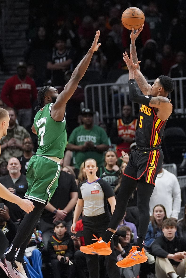El escolta de los Hawks de Atlanta, Dejounte Murray (5), dispara mientras el escolta de los Celtics de Boston, Jaylen Brown (7), defiende durante el tiempo extra en el partido de baloncesto de la NBA, el jueves 28 de marzo de 2024, en Atlanta. (AP Foto/John Bazemore)