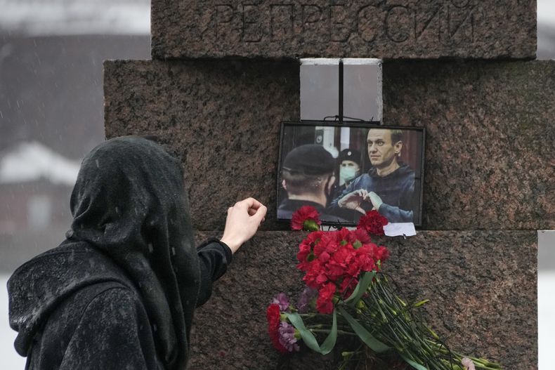 Una mujer toca la fotografía de Alexei Navalny tras dejar flores en homenaje al fallecido líder opositor ruso, en San Petersburgo, Rusia, el sábado 17 de febrero de 2024. (AP Foto/Dmitri Lovetsky)