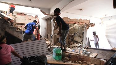 Varias personas retiran mercancías de una tienda dañada un día después de que un terremoto y varias réplicas sacudieran Catia La Mar, Venezuela, el jueves 25 de junio de 2026. (AP Foto/Jonathan Lanza)