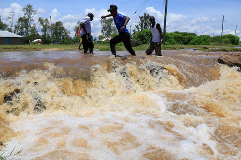 Personas intentan cruzar un tramo inundado de un camino luego de intensas lluvias, el 24 de marzo de 2026, en Nyakach, Kenia. (AP Foto/Andrew Kasuku, Archivo)
