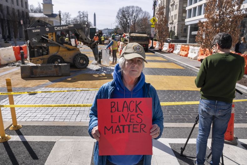 Jessica Sawyer, de 77 años, de Rockville, Maryland, sostiene un cartel que dice Black Lives Matter, el lunes 10 de marzo de 2025, mientras comienza la demolición del mural de Black Lives Matter en Washington. Estoy muy enojadA de que la administración Trump esté obligando al gobierno de D.C. a quitar algo que es tan importante, dice Sawyer. (AP Foto/Jacquelyn Martin)