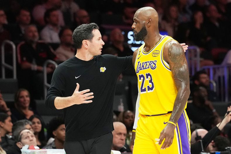 JJ Redick, a la izquierda, entrenador principal de los Lakers de Los Ángeles, habla con el alero estadounidense LeBron James (23) durante la segunda mitad de un juego de baloncesto de la NBA contra el Heat de Miami, el jueves 19 de marzo de 2026, en Miami. (Foto AP/Lynne Sladky)