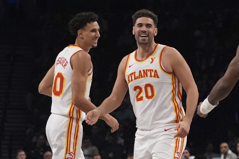 Zaccherie Risacher (izquierda) y Georges Niang, de los Hawks de Atlanta, festejan durante el partido del jueves 10 de abril de 2025, ante los Nets de Brooklyn (AP Foto/Frank Franklin II)
