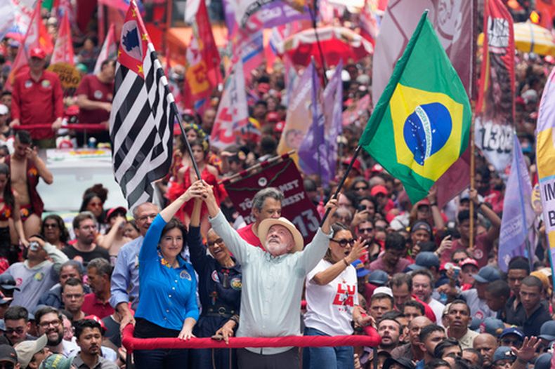 El presidente brasileño Luíz Inacio Lula da Silva, que se postula para la reelección, ondea banderas de Brasil y del estado de Sao Paulo en un mitin de campaña previo a la elección general, en Sao Paulo, el sábado 3 de octubre de 2026. (AP Foto/Andre Penner)