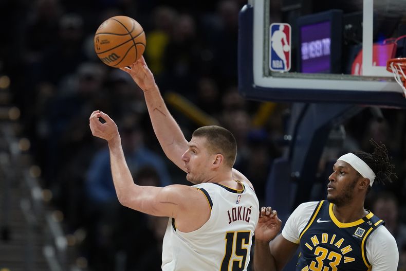 El serbio Nikola Jokic, de los Nuggets de Denver, envía un pase frente a Myles Turner, de los Pacers de Indiana, durante el duelo del martes 23 de enero de 2024 (AP Foto/Darron Cummings)