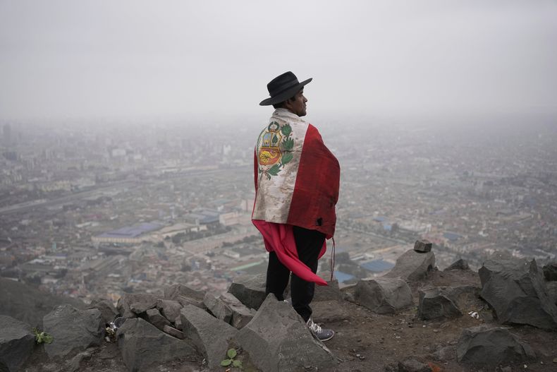 Un manifestante envuelto en una bandera de Perú observa la ciudad de Lima, el 27 de julio de 2025, durante una marcha contra una ley de amnistía que beneficiaría a miembros del ejército y civiles procesados por abusos de derechos humanos durante el conflicto armado del país. (AP Foto/Martín Mejía)