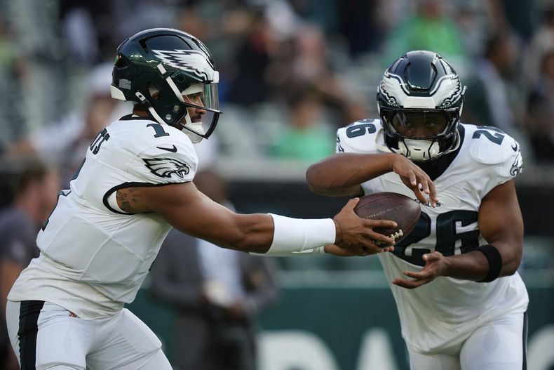 Jalen Hurts (1), quarterback de los Eagles de Filadelfia, entrega el balón a Saquon Barkley (26), corredor, durante los ejercicios de calentamiento previo a un partido de pretemporada de la NFL en contra de los Bengals de Cincinnati, el jueves 7 de agosto de 2025, en Filadelfia. (AP Foto/Matt Slocum)