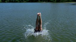 Un nadador se zambulle en el lago Cedar durante una alerta por calor extremo el lunes 13 de julio de 2026, en Minneapolis. (AP Foto/Ellen Schmidt)
