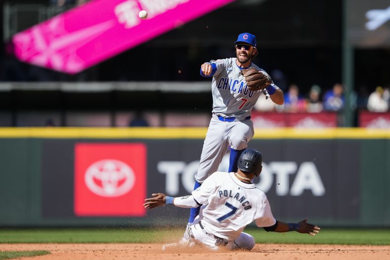 Dansby Swanson, arriba, de los Cachorros de Chicago, saca en segunda base a Jorge Polanco (7), de los Marineros de Seattle, y tira a primera para completar un doble play para retirar a Ty France y poner fin a la octava entrada del juego de béisbol del domingo 14 de abril de 2024, en Seattle. (AP Foto/Lindsey Wasson)