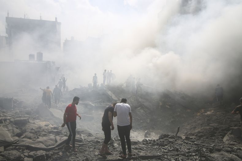 Palestinos buscan sobrevivientes luego de un ataque aéreo israelí, el jueves 12 de octubre de 2023, en el campamento de refugiados de Rafah, en el sur de la Franja de Gaza. (AP Foto/Hatem Ali)