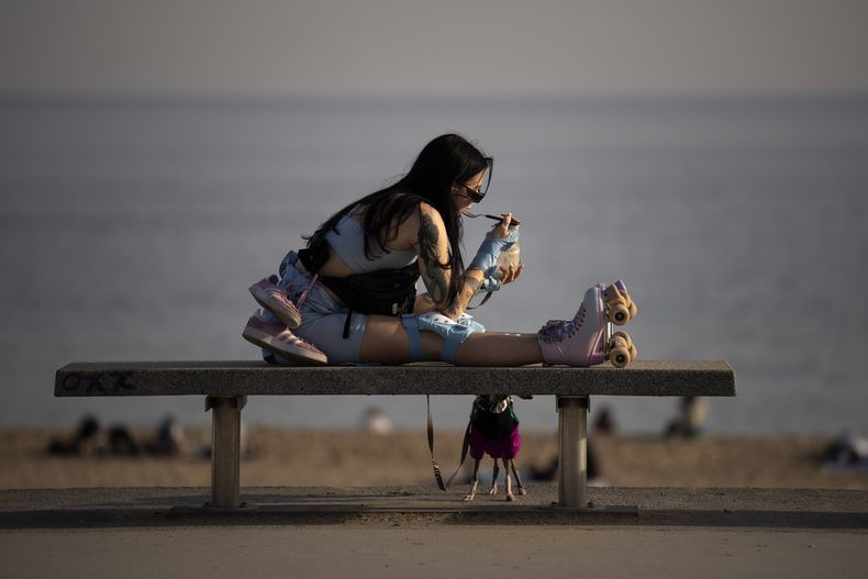 Una mujer come un helado frente a la playa en Barcelona, España, el viernes 26 de enero de 2024. (AP Foto/Emilio Morenatti)