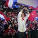 Santiago Peña, centro, candidato presidencial del partido Colorado, y el expresidente Horacio Cartes, derecha, sostienen las banderas de Paraguay y del partido en un mitin político en Asunción, Paraguay, el lunes 24 de abril de 2023. Las elecciones generales de Paraguay están programadas para 30 de abril. (Foto AP/Jorge Sáenz)