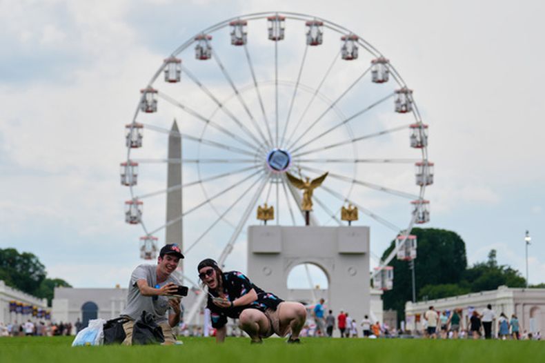Christine Bayly, a la derecha, y Jason Brown, a la izquierda, toman una foto mientras almuerzan en el National Mall, junto a la noria y una réplica del arco de triunfo, durante la Gran Feria Estatal de Estados Unidos, el viernes 26 de junio de 2026 en Washington. (AP Foto/Carolyn Kaster)