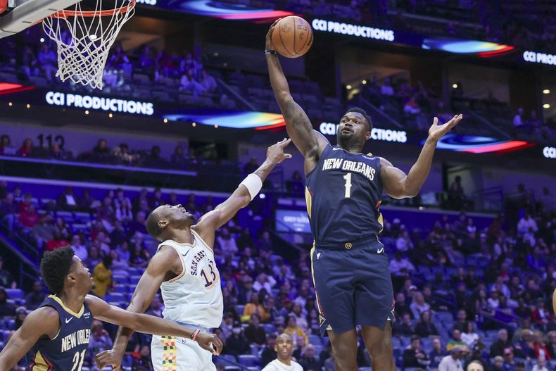 Zion Williamson (1), de los Pelicans de Nueva Orleans, atrapa un rebote defensivo ante el intento de Bismack Biyombo (18), de los Spurs de San Antonio, por ganarlo en la primera mitad del juego de baloncesto de la NBA, el domingo 23 de febrero de 2025, en Nueva Orleans. (AP Foto/Peter Forest)
