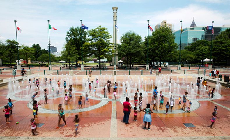ARCHIVO - Foto del 22 de julio del 2016, personas caminan sobre fuentes en forma de los aros olímpicos en el Parque Olímpico Centenario en Atlanta. (AP Foto/David Goldman, Archivo)