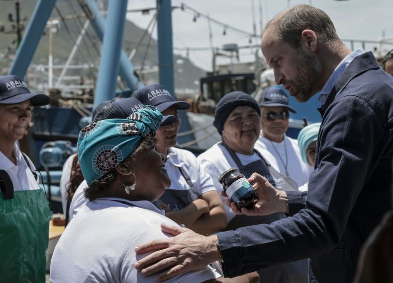 El príncipe Guillermo de Inglaterra recibe un regalo de una residente en Kalk Bay Harbour, cerca de Ciudad del Cabo, el 7 de noviembre de 2024. (Gianluigi Guercia/Pool Foto vía AP)