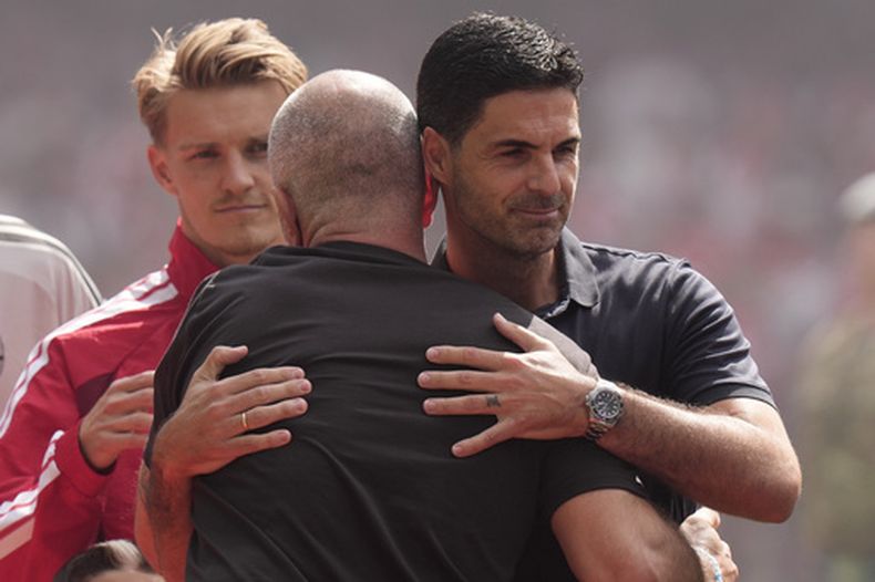 El director técnico del Arsenal, Mikel Arteta (derecha), abraza al entrenador del Manchester City, Enzo Maresca, antes del partido de fútbol de la final de la FA Community Shield entre el Arsenal y el Manchester City en Cardiff, Gales, el domingo 16 de agosto de 2026. (Foto AP/Alastair Grant)