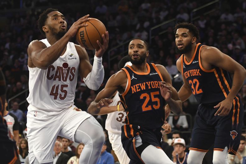 Donovan Mitchell, izquierda, de los Cavaliers de Cleveland, intenta anotar dejando atrás a Mikal Bridges, centro, y Karl-Anthony Towns, derecha, de los Knicks de Nueva York, durante la segunda mitad del juego de baloncesto de la NBA, el lunes 28 de octubre de 2024, en Nueva York. (AP Foto/Pamela Smith)
