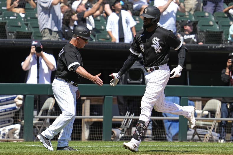 Luis Robert Jr., derecha, de Medias Blancas de Chicago, celebra con el coach de tercera Eddie Rodríguez después de batear cuadrangular solitario durante la cuarta entrada del juego de béisbol en contra de los Reales de Kansas City, en Chicago, el domingo 21 de mayo de 2023. (AP Photo/Nam Y. Huh)
