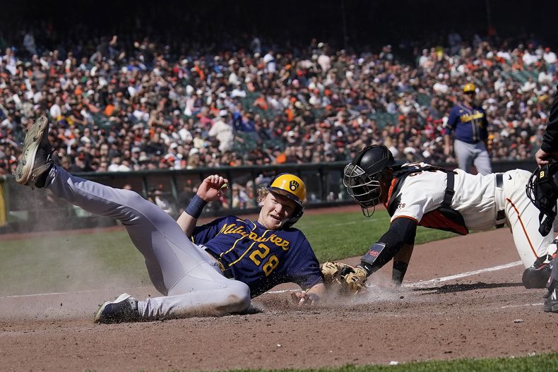 Joey Wiemer (28), de los Cerveceros de Milwaukee, anota ante el intento de toque del receptor de los Gigantes de San Francisco, Blake Sabol, durante la novena entrada del juego de béisbol en San Francisco, el domingo 7 de mayo de 2023. (AP Foto/Jeff Chiu)