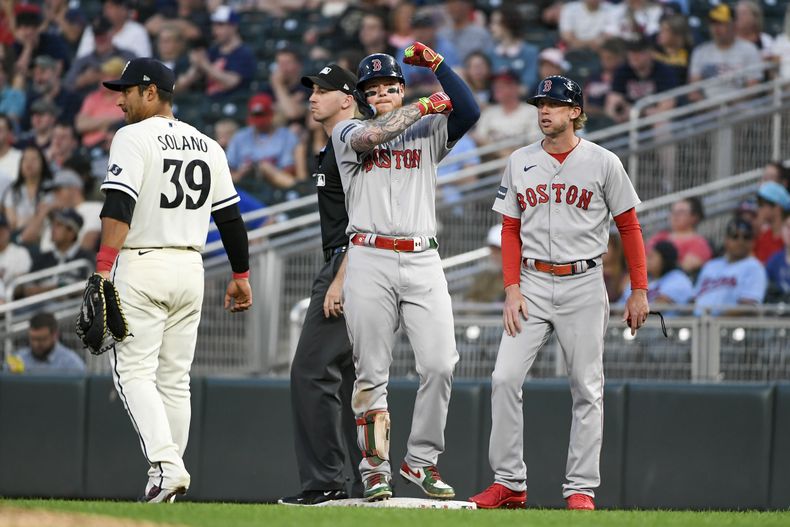 Alex Verdugo, centro, de los Medias Rojas de Boston, celebra después de batear un sencillo productor a un costado del primera base de los Mellizos de Minnesota, Donovan Solano (39) y el coach de primera base de Boston, Kyle Hudson, durante la octava entrada del juego de béisbol, el lunes 19 de junio de 2023, en Minneapolis. (AP Foto/Craig Lassig)