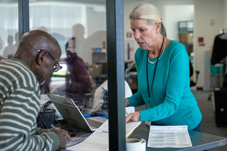Debbie Lewis, a la derecha, quien recibe votos anticipados, le entrega su boleta a Eddie Johnson, el miércoles 7 de octubre de 2026, en Cleveland. (AP Foto/Sue Ogrocki)