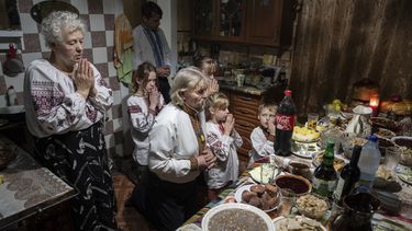 La familia Zelenchuk reza antes de su cena de Navidad en la localidad de Kryvorivnia, Ucrania, el domingo 24 de diciembre de 2023. (AP Foto/Evgeniy Maloletka)