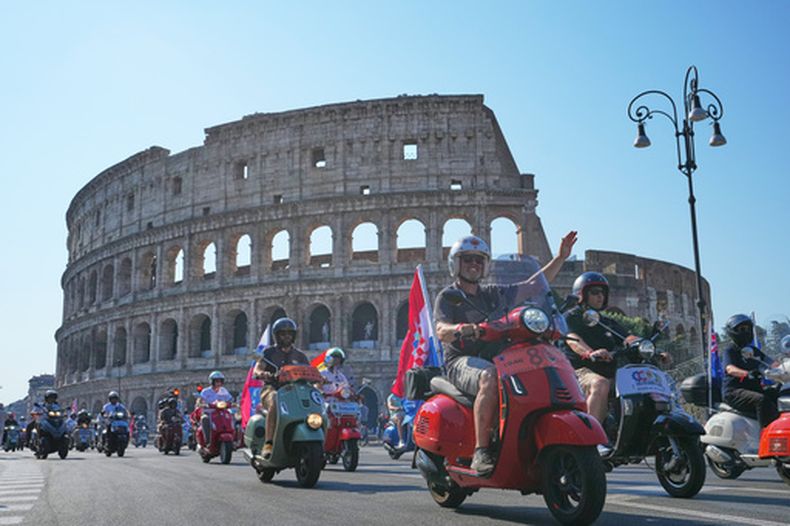 Entusiastas de Vespa desfilan frente al Coliseo durante las celebraciones por el 80mo aniversario del scooter Vespa, en Roma, el sábado 27 de junio de 2026. (AP Foto/Alessandra Tarantino)