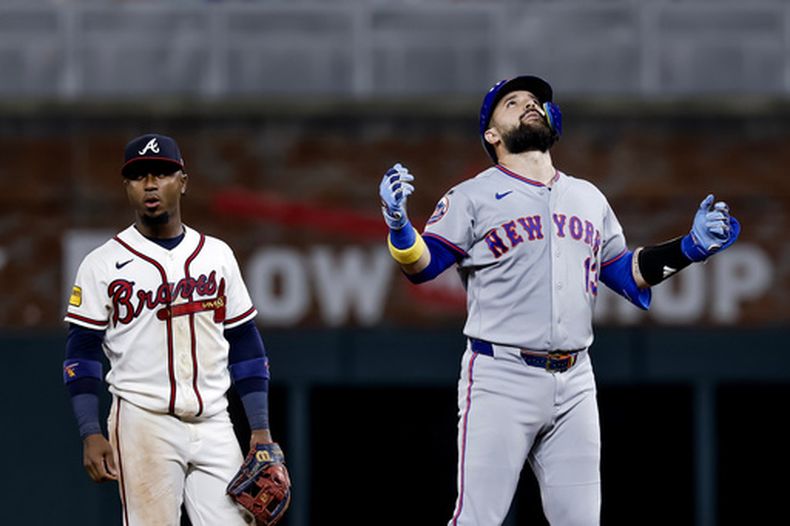 Luis Torrens, derecha, de los Mets de Nueva York, reacciona después de batear un doble productor de dos carreras mientras el segunda base de los Bravos de Atlanta, Ozzie Albies, izquierda, observa durante la décima entrada del juego de béisbol de Grandes Ligas del lunes 6 de julio de 2026, en Atlanta. (AP Foto/Erik S. Lesser)
