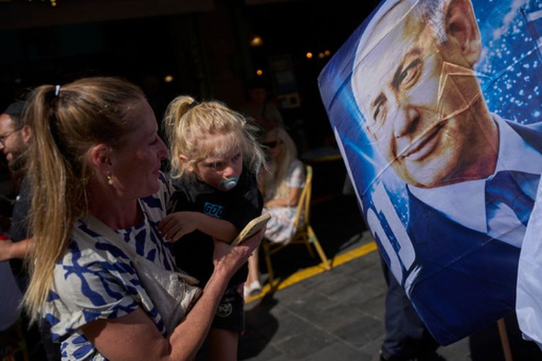 Una mujer con una niña frente a un afiche del primer ministro israelí Benjamin Netanyahu en Jerusalén, el 9 de octubre del 2026. (AP foto/Ohad Zwigenberg)