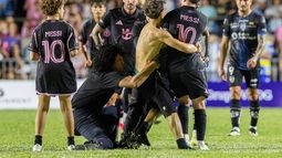 Un aficionado que irrumpió en la cancha sujeta a Lionel Messi al final del partido amistoso entre Inter Miami e Independiente del Valle de Ecuador, el jueves 26 de febrero de 2026, en Bayamón, Puerto Rico. (AP Foto/Alejandro Granadillo)