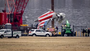 Una grúa descarga una pieza de los restos de un buque de salvamento en un camión de plataforma, cerca del lugar de los restos en el río Potomac de una colisión en pleno vuelo entre un avión de American Airlines y un helicóptero Black Hawk, en el Aeropuerto Nacional Ronald Reagan de Washington, el miércoles 5 de febrero de 2025, en Arlington, Virginia. (AP foto/Ben Curtis)